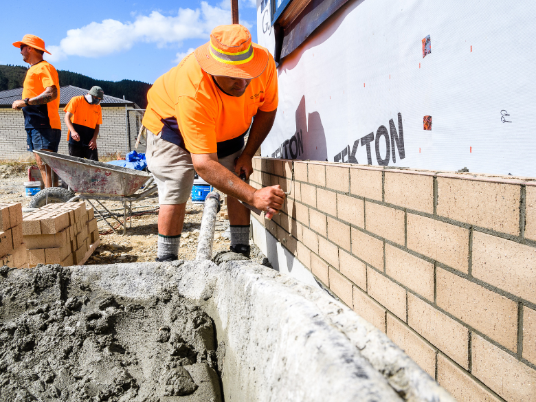 Worker grouting bricks in the sun on a construction site