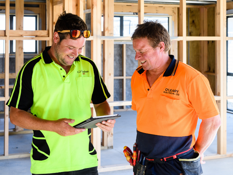 Two workers looking at a device on a construction site