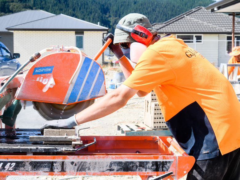 Construction worker wearing PPE cutting stone